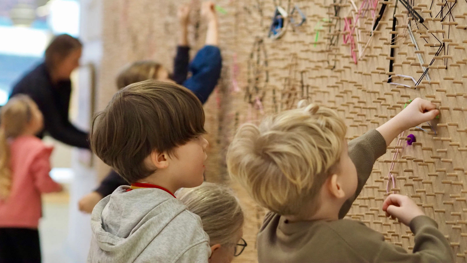 Børn der leger ved en væg af elastikker på et kunstmuseum